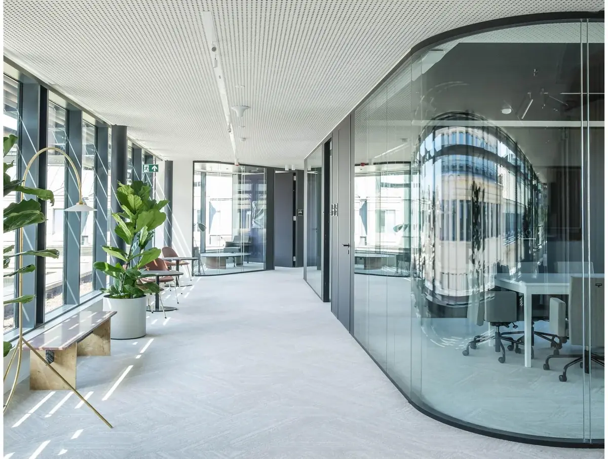 Couloir de bureaux modernes aux cloisons vitrées courbées, sans présence humaine